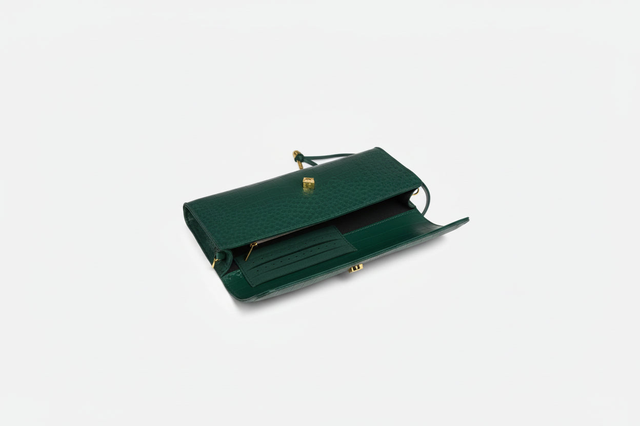 Green clutch bag with phone, wallet, and sunglasses on a white background