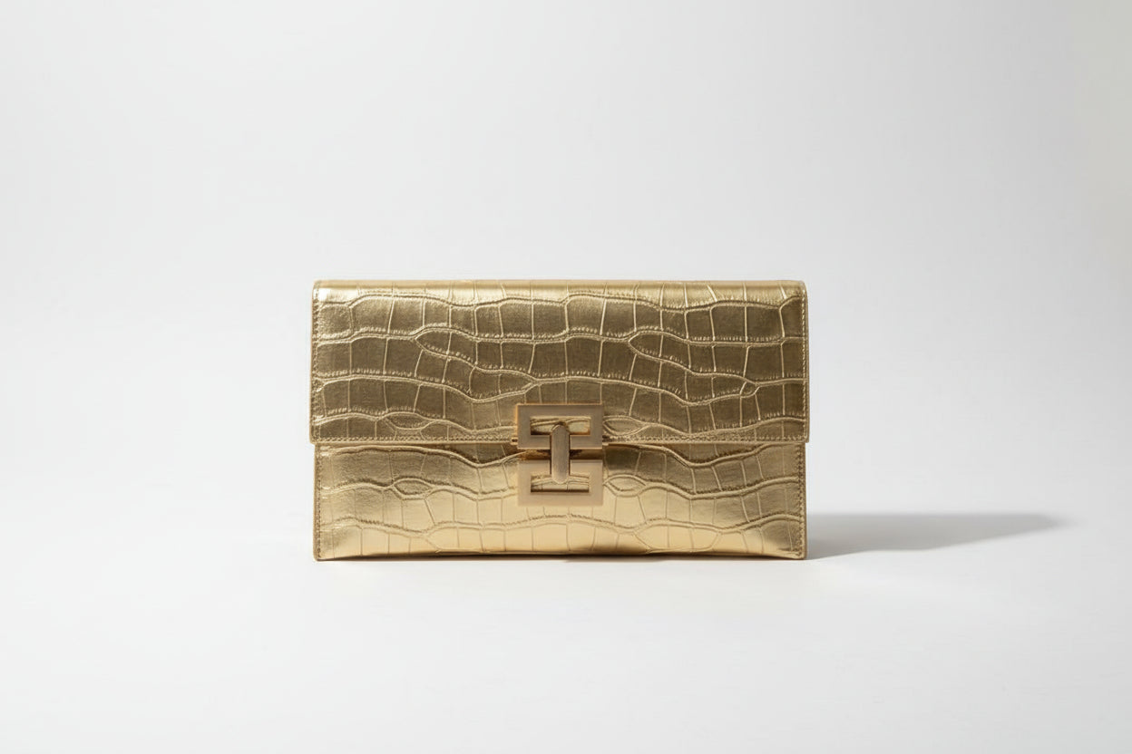 Gold clutch bag held by a person with a blurred background