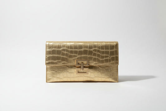 Gold clutch bag held by a person with a blurred background
