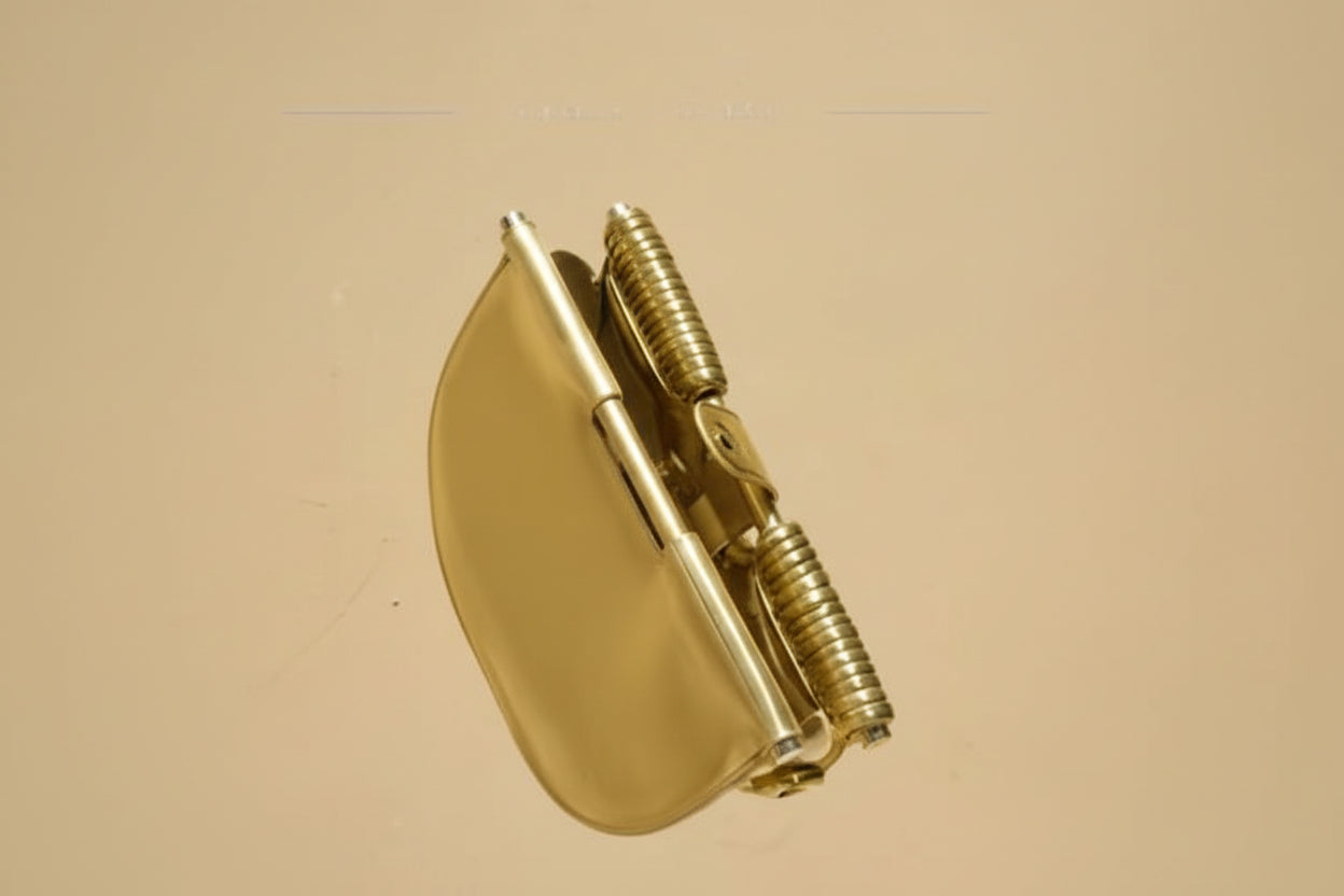 Hand holding a gold object against a beige background