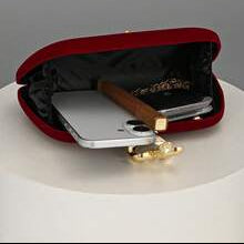 Red clutch with gold accents on a white surface,